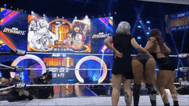 three women are standing in a wrestling ring with the word dynamite on the screen