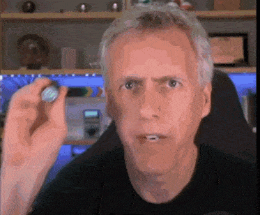 a man with gray hair is holding a small object in his hand