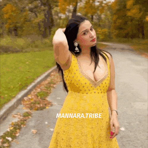 a woman in a yellow dress is standing on the side of a road with the words mannara.tribe above her