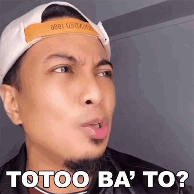 a man wearing a baseball cap is making a funny face and the words totoo ba ' to appear on his face .
