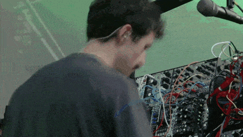 a man in a black shirt is working on a mixer with a lot of wires coming out of it
