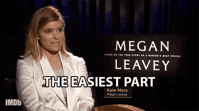 a woman in a white jacket sits in front of a sign that says megan leavey