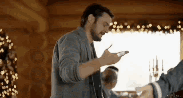 a man with a beard is standing in front of a christmas tree in a cabin .