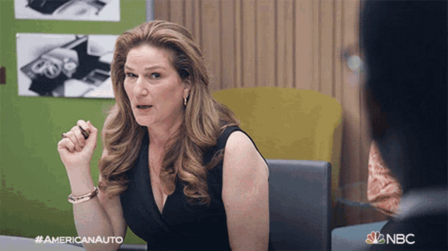 a woman is sitting at a desk with a nbc logo on the bottom