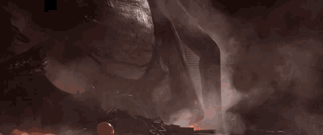 a man laying on the ground in a dark room with a fire in the background