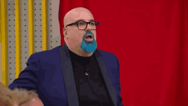 a bald man with a blue beard and glasses is wearing a blue suit