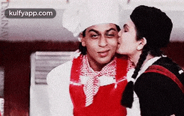 a woman is kissing a man on the cheek while wearing a chef 's hat .
