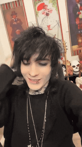 a person with a tattoo on their face is wearing a black shirt and a silver necklace