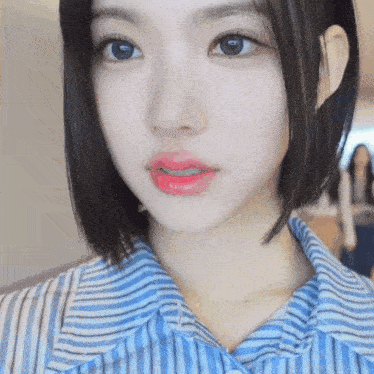 a close up of a woman 's face wearing a striped shirt