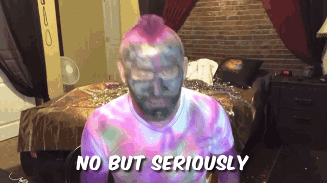 a man with a pink mohawk is sitting in front of a bed and says no but seriously