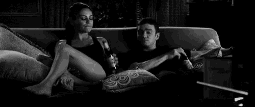 a man and a woman are sitting on a couch watching a movie .