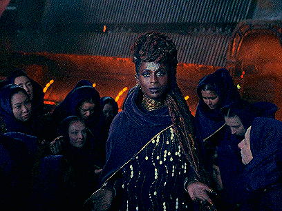 a woman in a purple dress is standing in front of a group of women