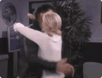 a man and a woman are hugging in a room with a palm tree in the background