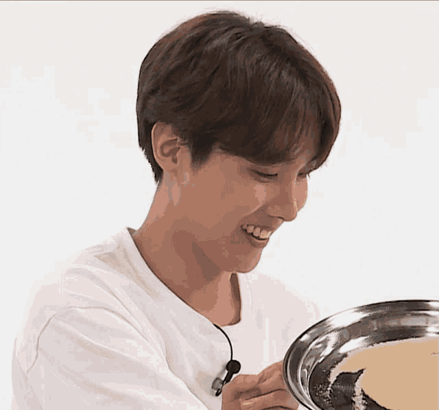 a young man in a white shirt is smiling while holding a tray of food