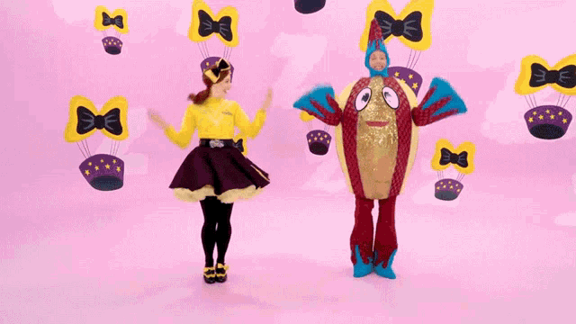 a woman in a yellow shirt is dancing next to a person in a red costume