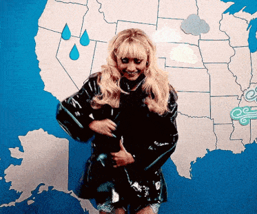 a woman in a black raincoat standing in front of a map of the united states