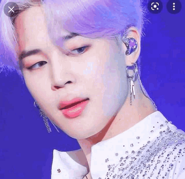 a close up of a person wearing purple hair and earrings