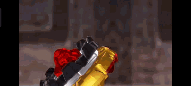 a close up of a red and gold toy that looks like a sword and a hammer .