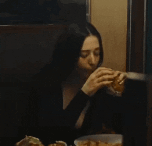 a woman is eating a sandwich in a restaurant booth