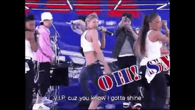 a group of people are dancing and singing on a stage with a sign that says oh ! on it