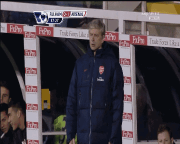 a man in an arsenal jacket stands in a dugout