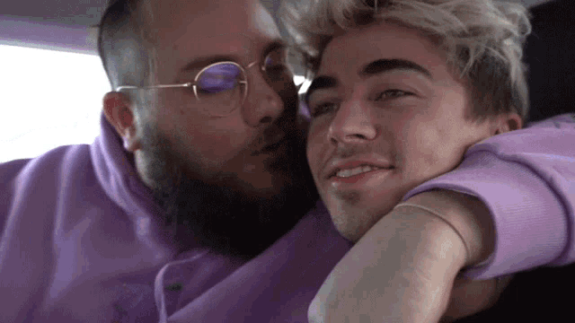 a man kissing another man on the cheek in a car
