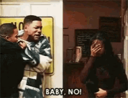 a man is holding a baby while a woman covers her face and says baby no !