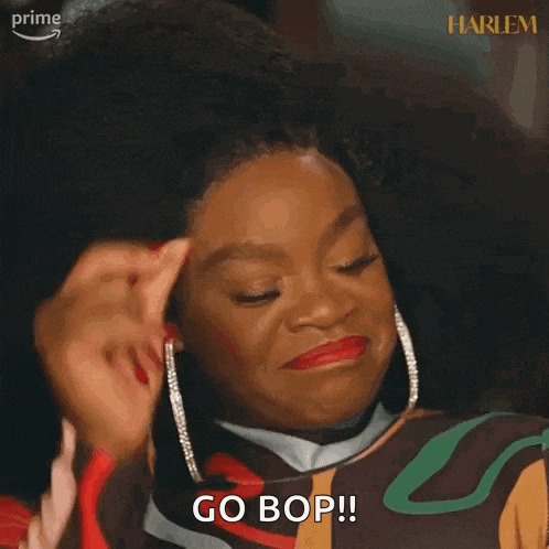 a woman is holding her finger to her forehead and saying go bop .