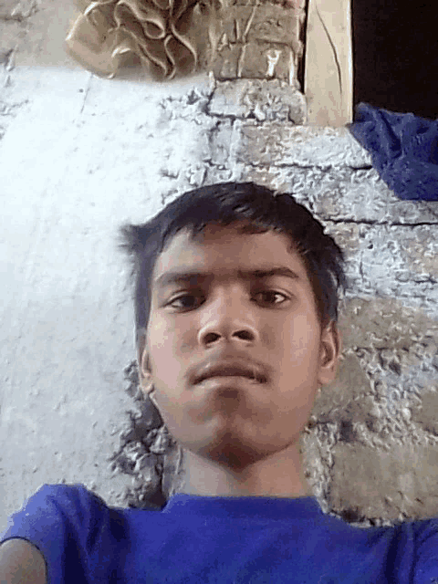 a young boy taking a selfie with a blue shirt on