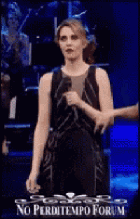 a woman in a black dress is holding a microphone in front of a band .