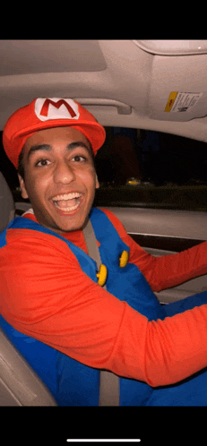 a man in a mario costume is driving a car and smiling