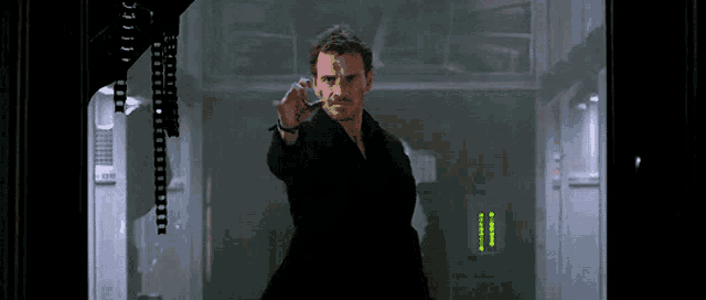 a man standing in a dark room pointing at something
