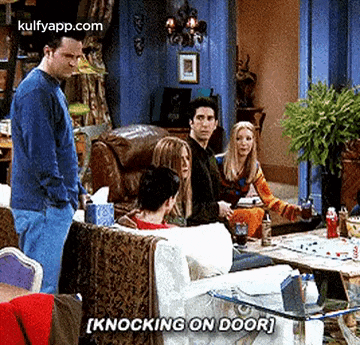a man is standing in front of a group of people sitting on a couch .