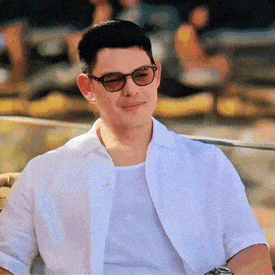 a man wearing sunglasses and a white shirt looks at the camera