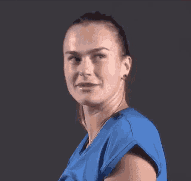 a woman in a blue shirt is making a funny face while looking at the camera .