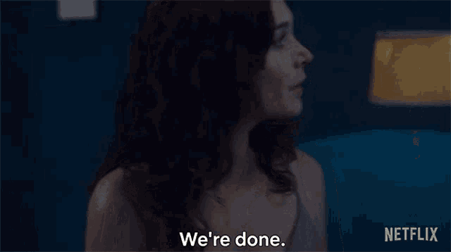 a woman in a bra is standing in front of a lamp and says we 're done .