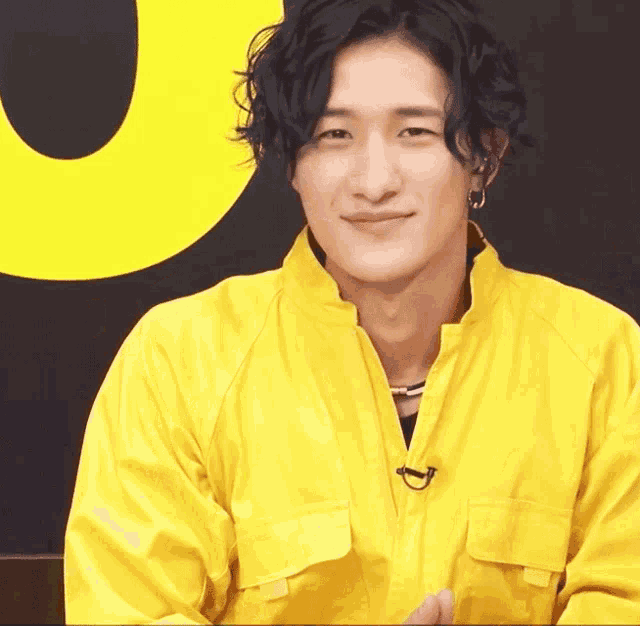 a man in a yellow jacket is smiling in front of a large u