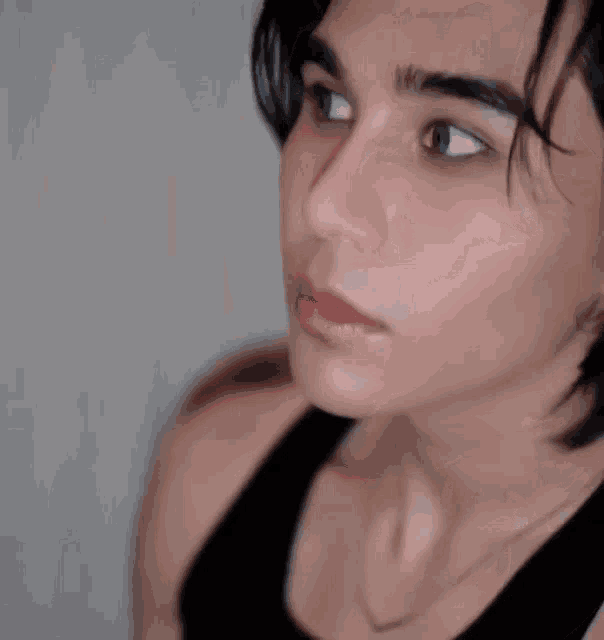 a close up of a woman 's face with a black tank top on