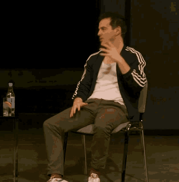 a man is sitting in a chair with a bottle of water in the background