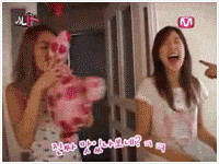 two girls are playing with a stuffed animal in front of a mnet sign