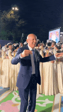 a man in a suit and tie stands in front of a crowd of people