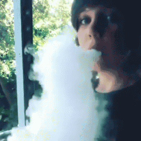 a woman is blowing smoke out of her mouth while looking out a window .