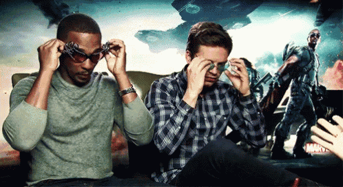 two men wearing sunglasses are sitting in front of a movie poster .