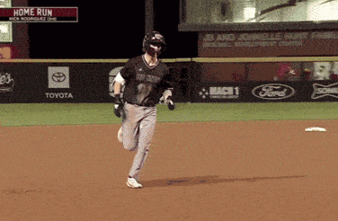 a baseball player is running on the field with a home run sign above him