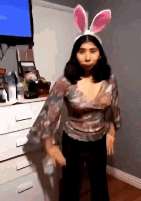 a girl wearing bunny ears is dancing in front of a television