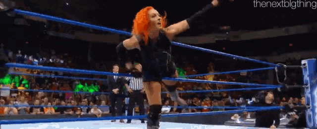 a female wrestler is jumping in the air in a wrestling ring while a referee watches