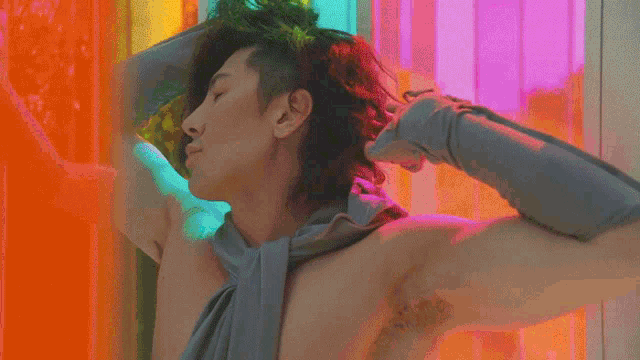 a man without a shirt is adjusting his hair in front of a colorful wall