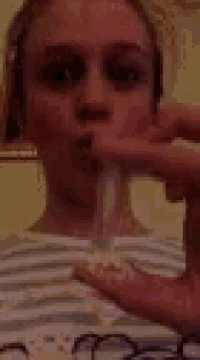 a woman is holding a fork in her mouth and making a funny face .