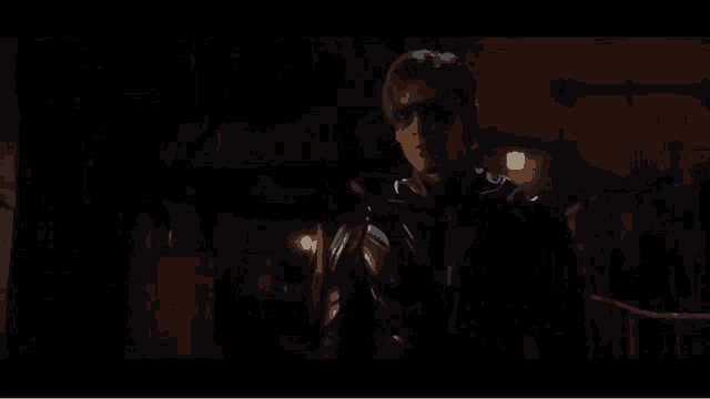 a man in a black superhero costume is standing in the dark .