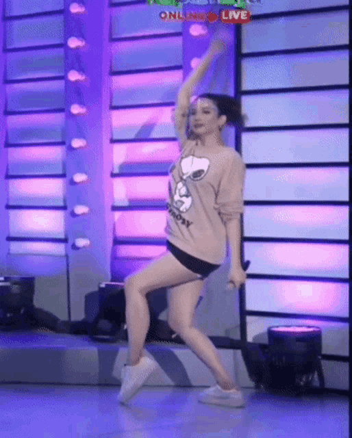 a woman in a snoopy sweater is dancing on a stage while holding a microphone .